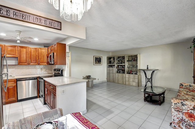 kitchen featuring ceiling fan with notable chandelier, a textured ceiling, stainless steel appliances, and decorative backsplash