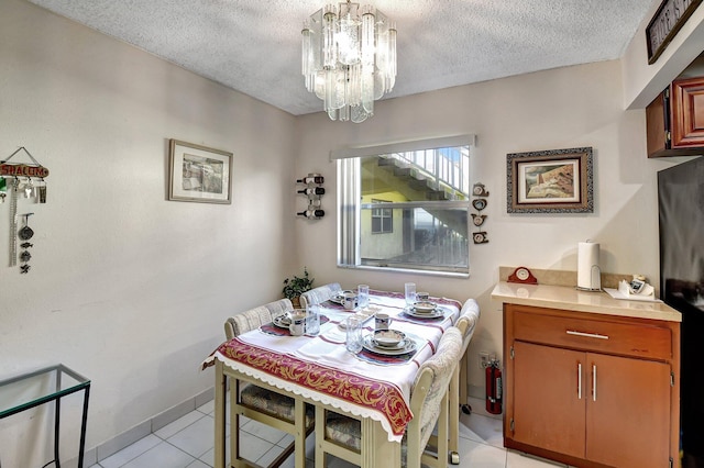 dining space featuring a textured ceiling, a notable chandelier, and light tile patterned floors