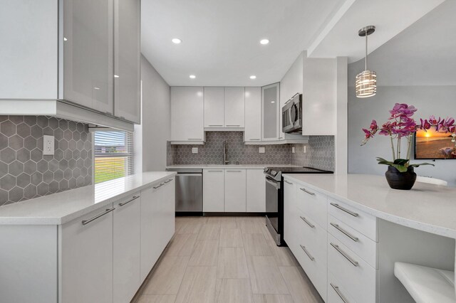164 Normandy D, Delray Beach, FL 33484 - kitchen with decorative backsplash, modern cabinets, light countertops, white cabinets, and appliances with stainless steel finishes