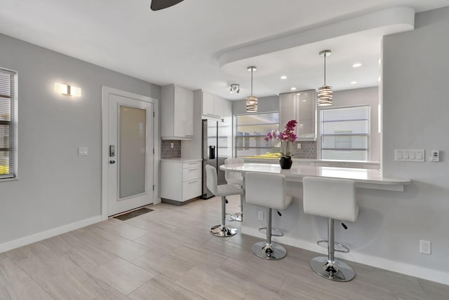 164 Normandy D, Delray Beach, FL 33484 - kitchen featuring a peninsula, a kitchen bar, white cabinetry, stainless steel refrigerator with ice dispenser, and light countertops