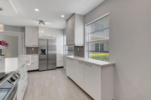 164 Normandy D, Delray Beach, FL 33484 - kitchen with recessed lighting, light countertops, tasteful backsplash, appliances with stainless steel finishes, and white cabinetry