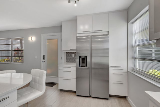164 Normandy D, Delray Beach, FL 33484 - kitchen featuring white cabinets, stainless steel fridge with ice dispenser, light stone counters, and decorative backsplash