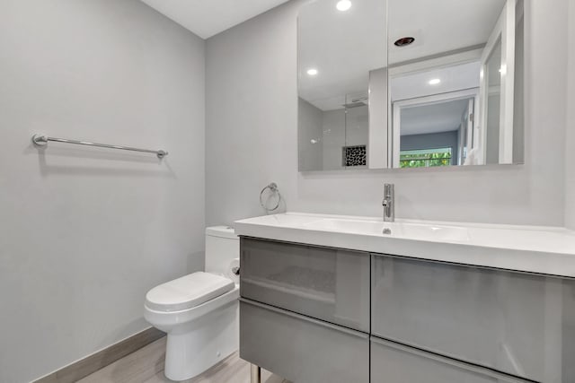 164 Normandy D, Delray Beach, FL 33484 - full bathroom featuring wood finished floors, toilet, vanity, a walk in shower, and baseboards