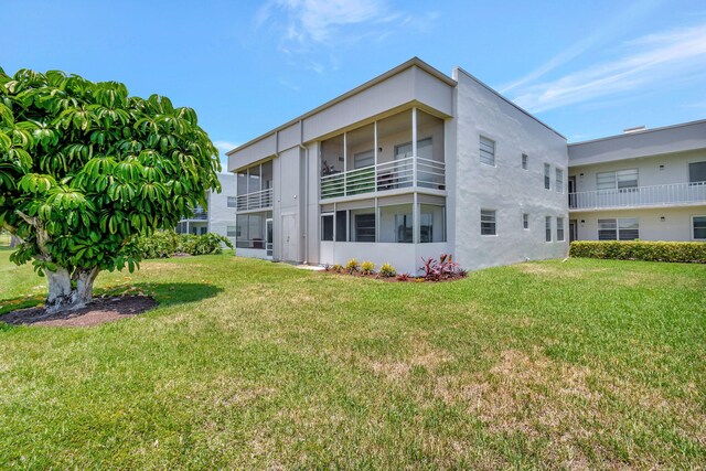 164 Normandy D, Delray Beach, FL 33484 - back of property with a lawn and stucco siding