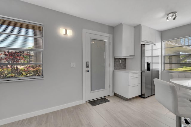 164 Normandy D, Delray Beach, FL 33484 - kitchen with stainless steel fridge, light wood finished floors, light countertops, white cabinets, and baseboards