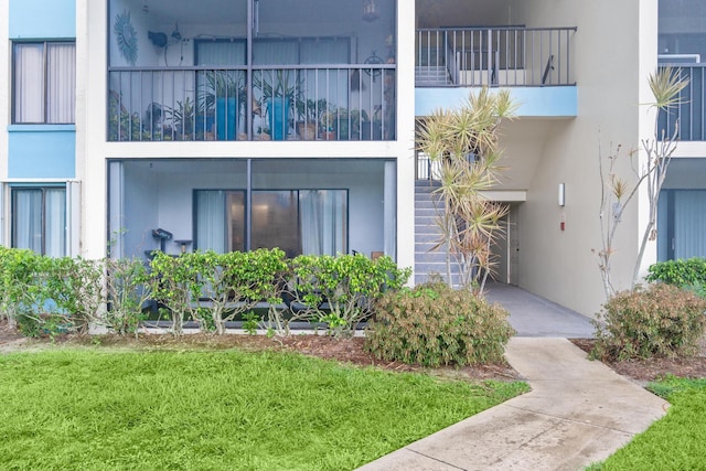 view of exterior entry featuring a yard and stucco siding