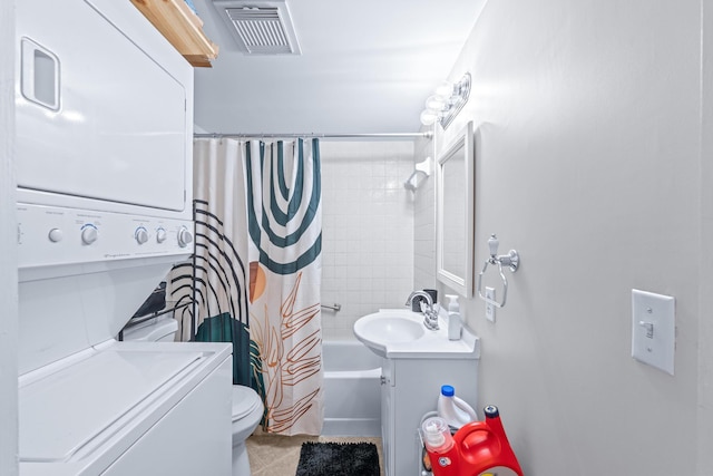 full bathroom featuring vanity, shower / tub combo with curtain, stacked washing maching and dryer, tile patterned flooring, and toilet