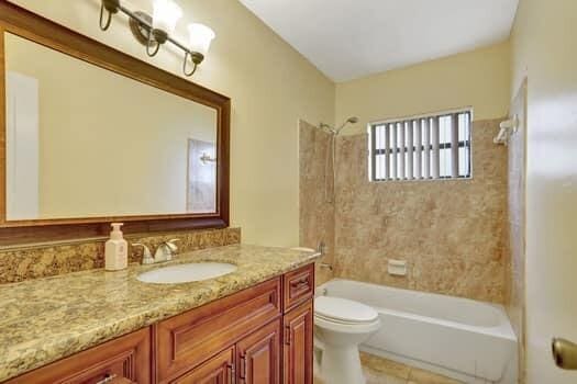 full bathroom with tile patterned floors, tiled shower / bath, toilet, and vanity