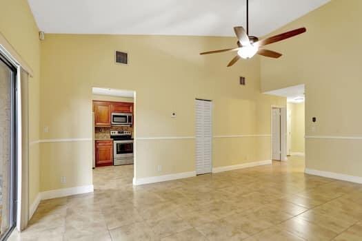 unfurnished living room with ceiling fan and high vaulted ceiling