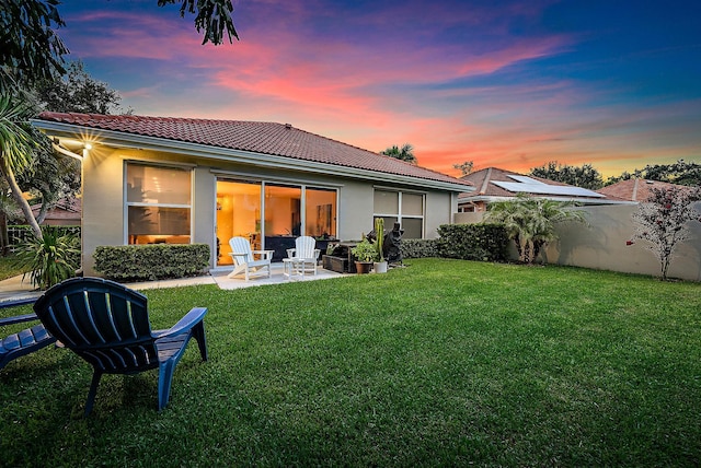 back house at dusk with a yard and a patio