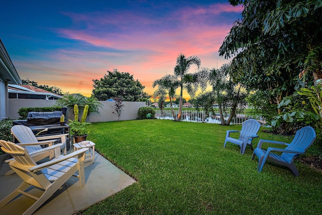 yard at dusk with a patio and a water view