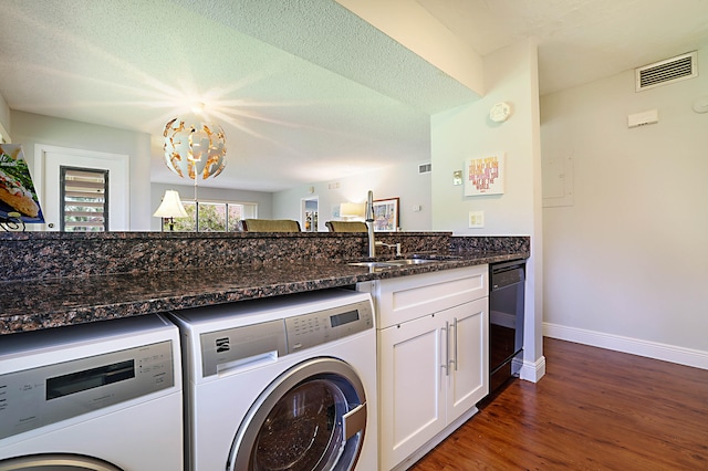 laundry area featuring a notable chandelier, a textured ceiling, washer and dryer, dark hardwood / wood-style flooring, and sink