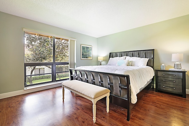 bedroom with dark hardwood / wood-style floors and a textured ceiling