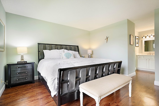 bedroom featuring dark hardwood / wood-style flooring, ensuite bathroom, and sink