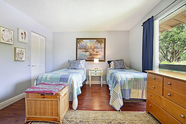 bedroom with a closet, a textured ceiling, and dark hardwood / wood-style floors