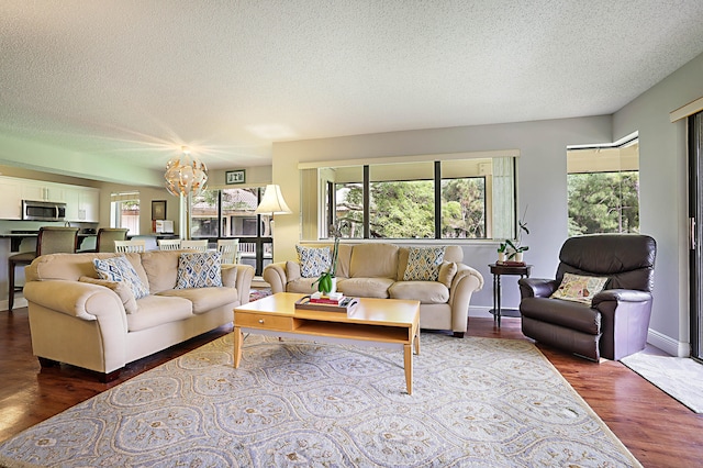 living room featuring a textured ceiling, an inviting chandelier, and dark hardwood / wood-style floors