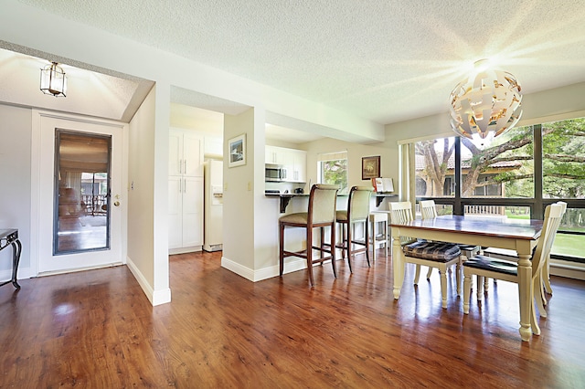 unfurnished dining area with a textured ceiling, an inviting chandelier, and dark hardwood / wood-style floors