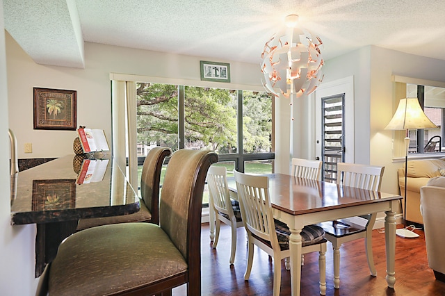 dining space with plenty of natural light, dark hardwood / wood-style flooring, a notable chandelier, and a textured ceiling