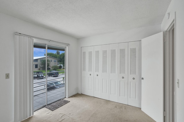 carpeted bedroom with a textured ceiling, access to exterior, and a closet