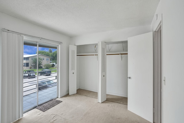 unfurnished bedroom featuring light carpet, a textured ceiling, and two closets