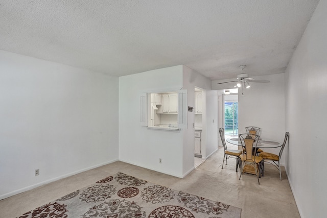 interior space with a textured ceiling, light colored carpet, and ceiling fan