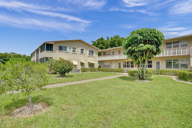 view of front of house featuring a balcony and a front lawn