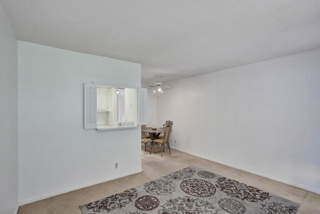 unfurnished room featuring ceiling fan, light colored carpet, and a textured ceiling