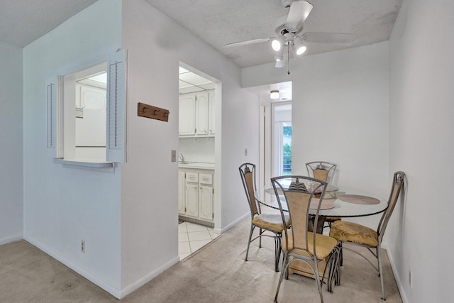 dining space with light colored carpet, a textured ceiling, and ceiling fan