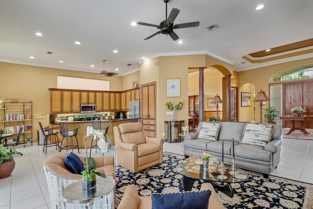 living room featuring crown molding, ceiling fan, light tile patterned floors, and ornate columns