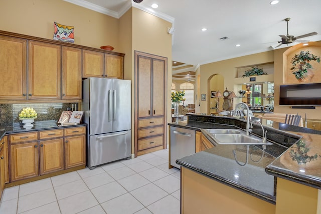 kitchen with dark stone counters, ornamental molding, stainless steel appliances, sink, and ceiling fan