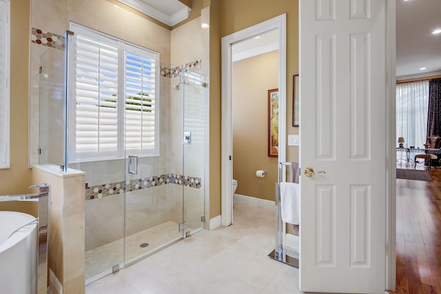 bathroom with toilet, ornamental molding, hardwood / wood-style floors, and plus walk in shower