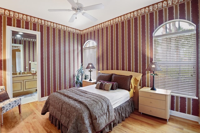 bedroom featuring ensuite bath, light hardwood / wood-style flooring, sink, and ceiling fan