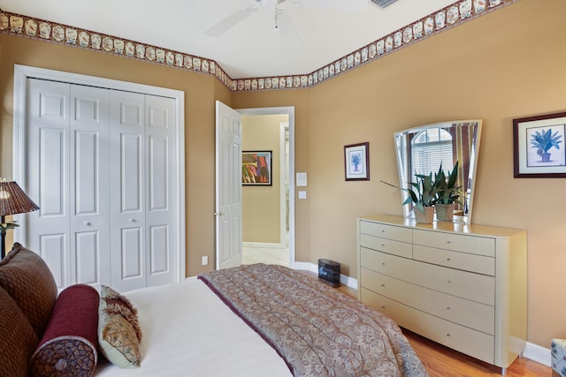 bedroom with light hardwood / wood-style flooring, ceiling fan, and a closet