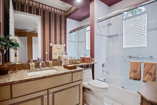 full bathroom with combined bath / shower with glass door, vanity, toilet, and ceiling fan