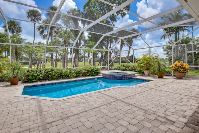 view of pool featuring glass enclosure, a patio, and an in ground hot tub