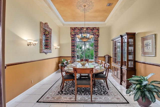 dining room with a notable chandelier, a tray ceiling, and light tile patterned flooring