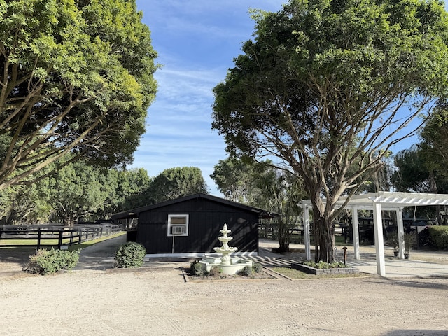 view of outdoor structure featuring a pergola and fence