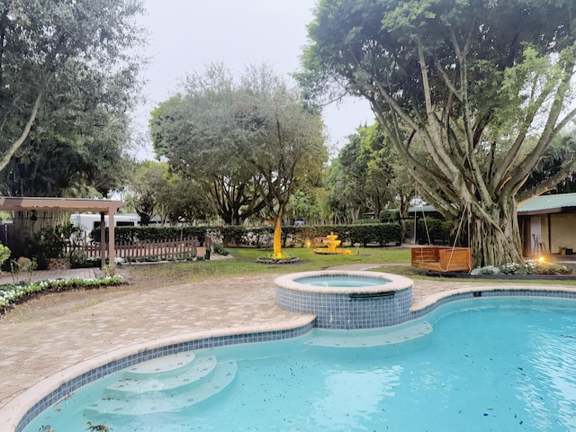 view of pool featuring fence, a pool with connected hot tub, and a patio area