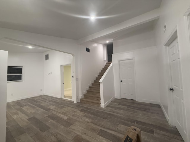 below grade area featuring stairway, baseboards, visible vents, and dark wood-style flooring