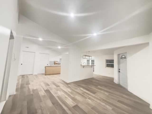 unfurnished living room featuring wood-type flooring and lofted ceiling