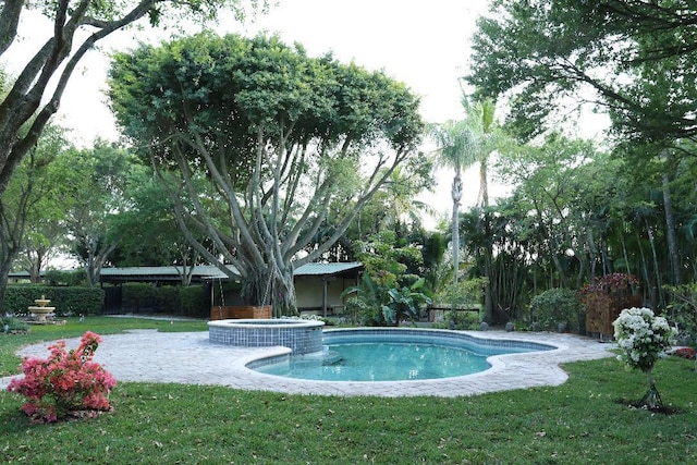 view of pool featuring a yard, fence, and a pool with connected hot tub