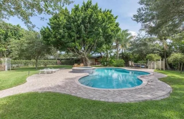 view of pool with an in ground hot tub, a patio, and a lawn