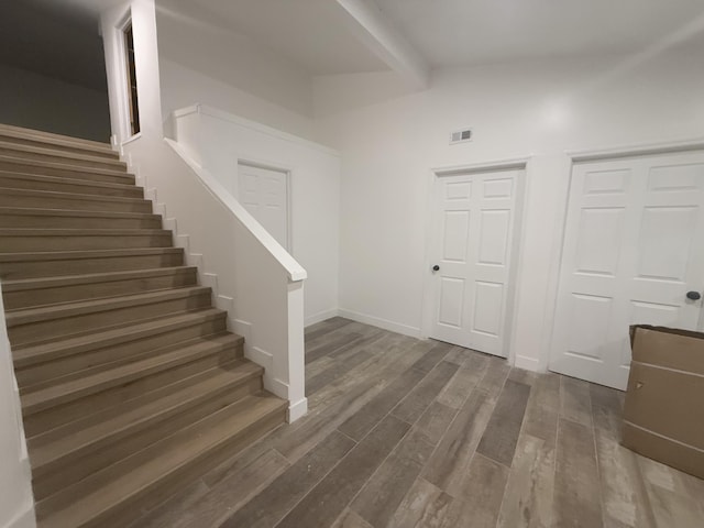 interior space with wood finished floors, visible vents, baseboards, beam ceiling, and stairs