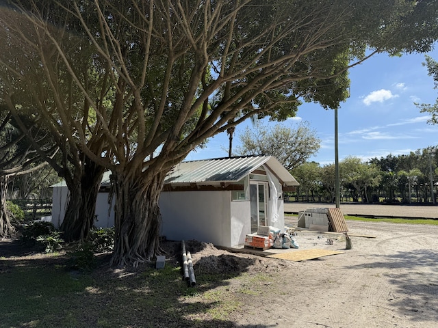 exterior space featuring stucco siding, an outdoor structure, and metal roof