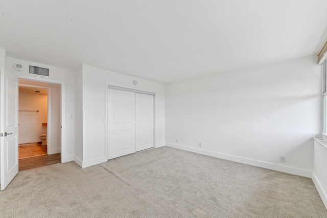 unfurnished bedroom featuring light colored carpet and a closet