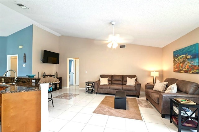 tiled living room featuring a textured ceiling, vaulted ceiling, sink, and ceiling fan