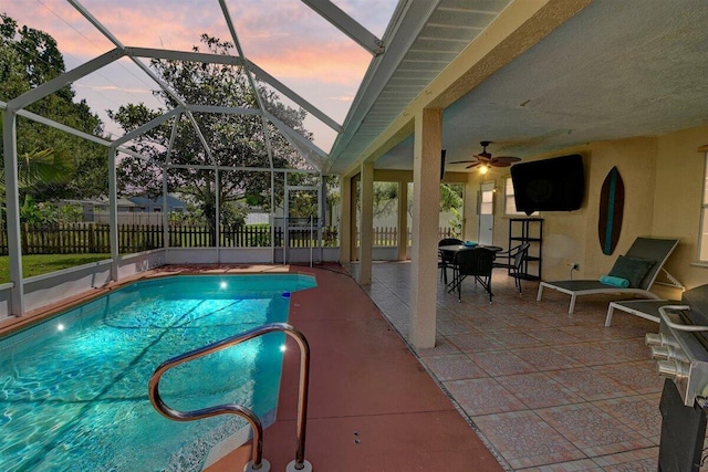 pool at dusk with ceiling fan, a lanai, and a patio