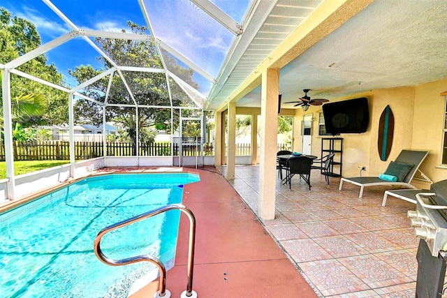 view of swimming pool with glass enclosure, ceiling fan, and a patio