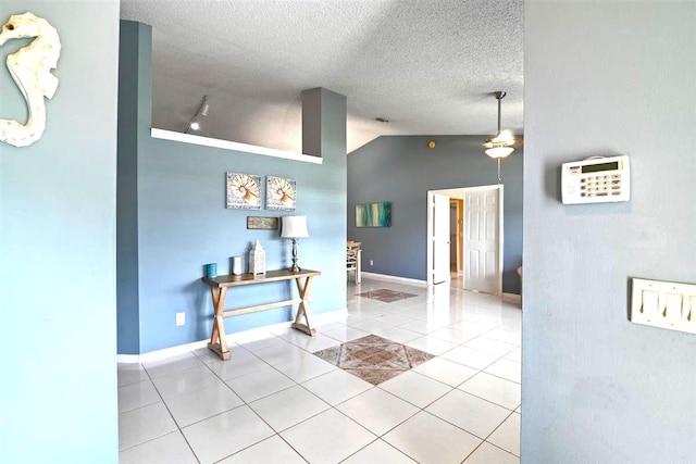 interior space with light tile patterned floors, a textured ceiling, and vaulted ceiling