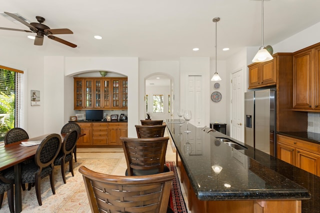 kitchen with ceiling fan, sink, stainless steel fridge, and a breakfast bar area